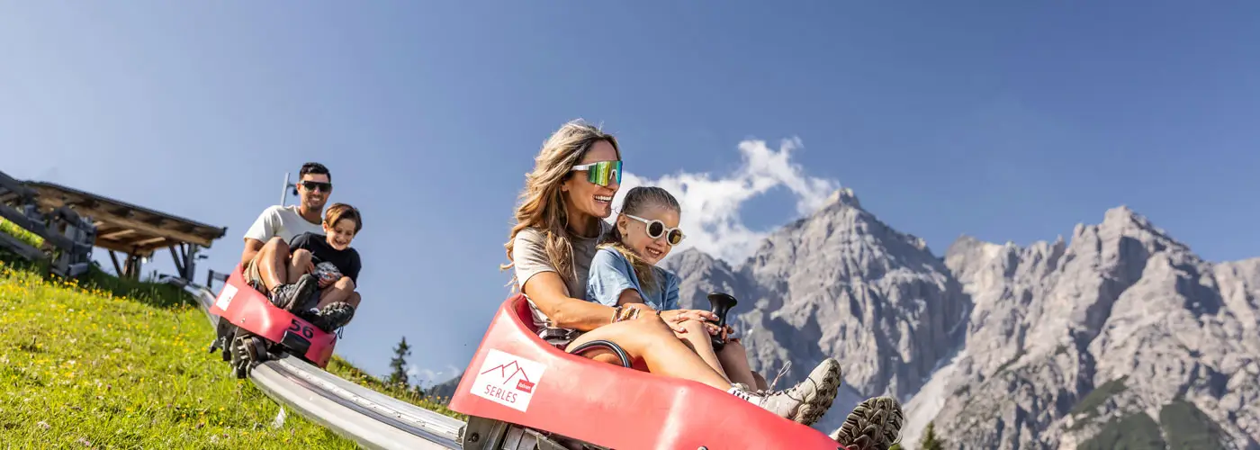 Familie fährt Sommerrodelbahn im Gebirge