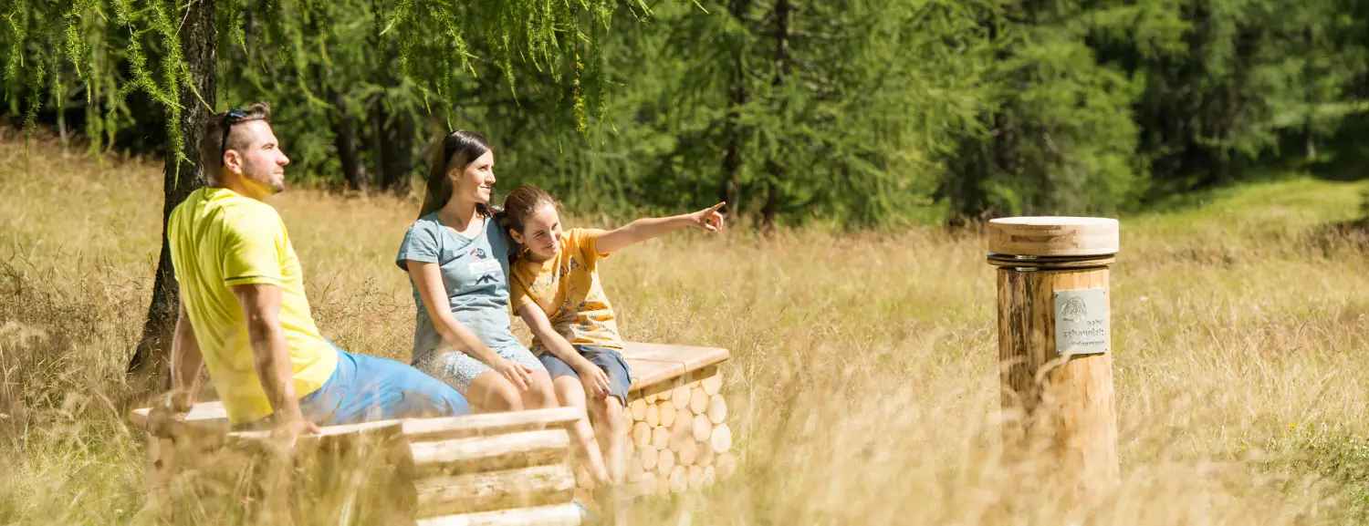 Familie sitzt auf einer Holzbank.
