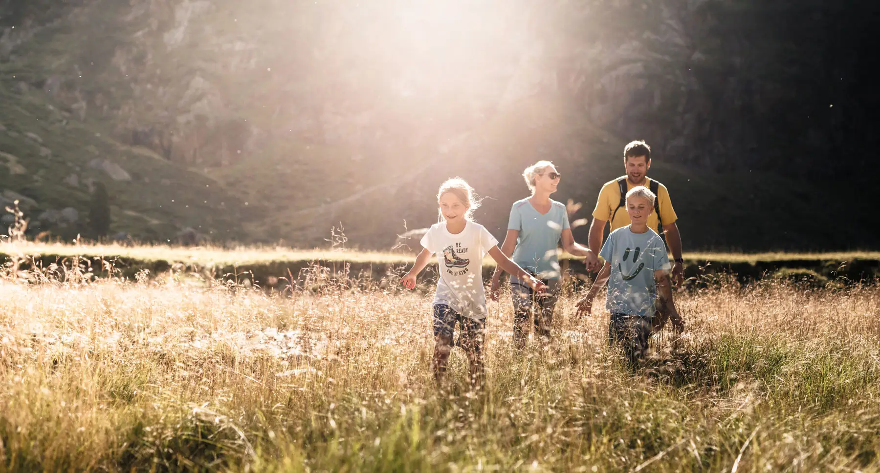 Familie läuft durch hohes Gras.
